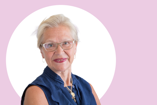 Sirkka Heinonen lähikuvassa, taustalla vaaleanpunaista ja valkoista.