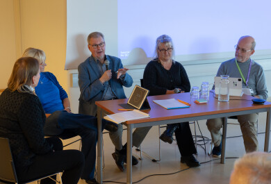 Ihmisiä puhumassa salin edustalla paneelissa