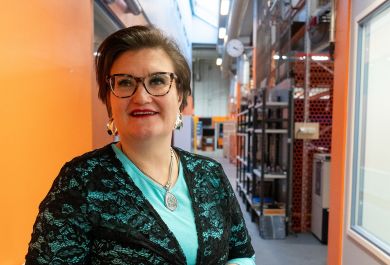 Heidi Piili konetekniikan hallissa pitkällä käytävällä, kasoo kohti kameraa, vieressä oranssi seinä
