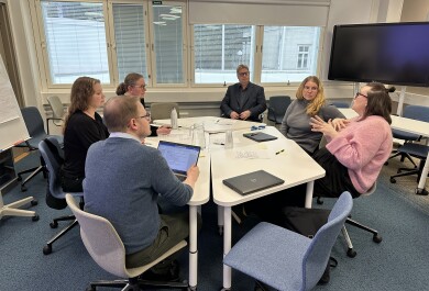 Six people sitting around a table discussing