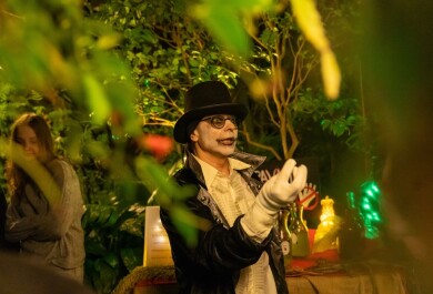 Silinterihattuun ja mustavalkoiseen asuun ja halloween-meikkiin pukeutunut tutkija Halloween-tapahtumassa kasvitieteellisessä puutarhassa