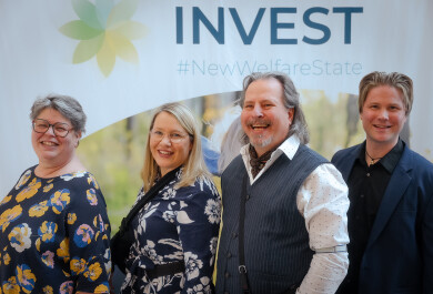 neljä ihmistä seisoo hymyilevinä INVEST-messuseinän edessä