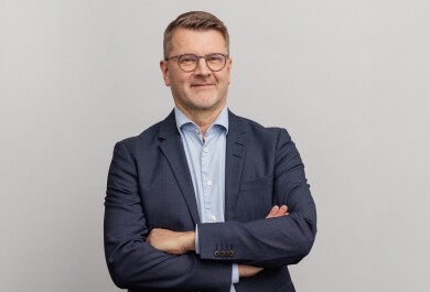 Lauri Tuomi lähikuvassa, harmaa tausta.