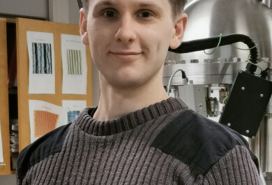 Väittelijän potrettikuva, taustalla näkyy laboratoriolaitteistoa