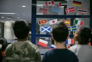 Lapsia eri maiden lippuja sisältvän seinämän edessä.