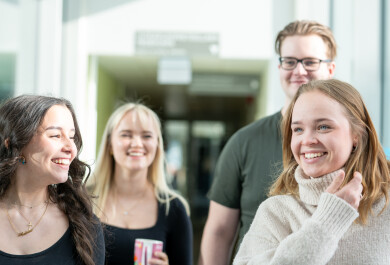 Neljä hymyilevää opiskelijaa Publicumin käytävällä
