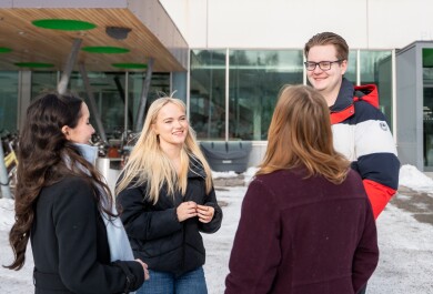 Neljä opiskelijaa keskustelee Turun yliopiston Publicum-rakennuksen edessä