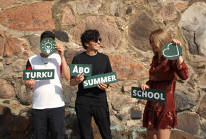 three students holding turku åbo summer school signs