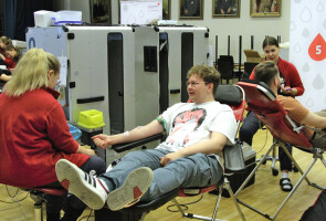 Opiskelija istuu hoitajaa vastapäätä verenluovutuspenkissä