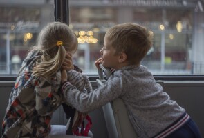 Kuvassa kouluikäiset lapset juttelevat bussissa.