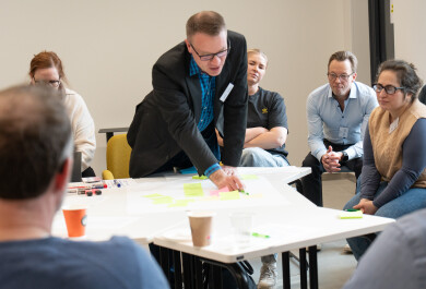 Ihmisiä kirjoittamassa yhdessä tussilla isolle paperille