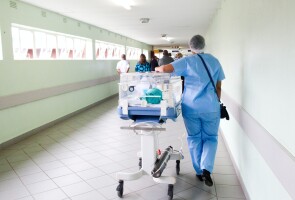 Sairaanhoitaja kuljettaa potilasta sairaalassa.
