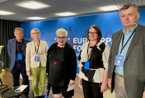 Viisi henkilöä Eurooppa-foorumin taustaseinän edessä