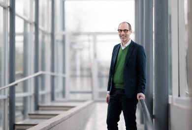 Dekaani Jaakko Järvi henkilökuvassa valoisalla lasiseinäisellä käytävällä kampuksella