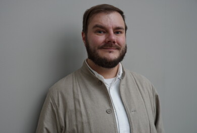 Mies kuvattuna seinän edustalla.