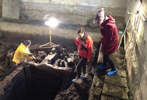 Kolme ihmistä arkeologisilla kaivauksilla.