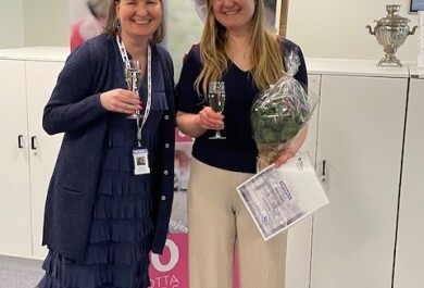 Kaksi henkilöä katsoo kameraan ja hymyilee, käsissään kuohuviinilasit ja toisella myös kukkakimppu ja diplomi.