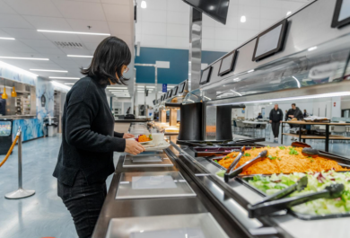 Henkilö ottamassa ruokaa lounaslinjastolla.