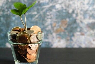 Plant growing out of glass full of coins