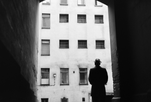 Mies seisoo synkässä kaupungin porttikongissa selin kameraan 1950-luvulla.