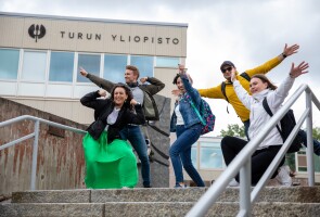 Opiskelijaryhmä poseeraa Yliopistonmäellä Tiedon portaiden yläpäässä