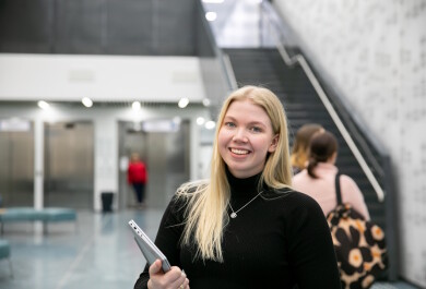 Opiskelija on menossa luennolle yliopiston aulassa läppäri mukanaan.