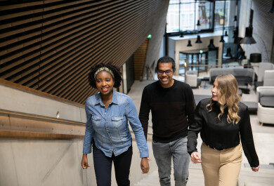 Three students ascending stairs in the lobby of Aurum