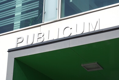 Publicum-rakennuksen nimikyltti pääoven yläpuolella.