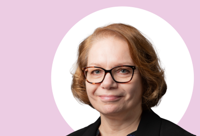 Marjo Kaartinen lähikuvassa, taustalla vaaleanpunaista ja valkoista.