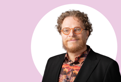 Tapio Salakoski lähikuvassa, taustalla vaaleanpunaista ja valkoista.