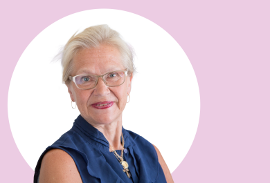 Sirkka Heinonen lähikuvassa, taustalla vaaleanpunaista ja valkoista.