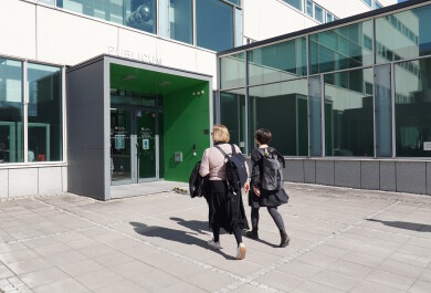 Kaksi naista kävelemässä sisälle rakennukseen.