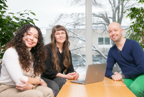 three doctoral researchers sitting at a table smiling
