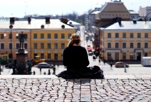 Nuori ihminen istuu Helsingin Suurkirkon portaiden yläpäässä yksin.