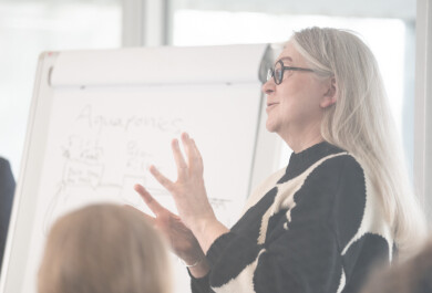 Henkilö pitämässä esitelmää fläppitaulun edessä