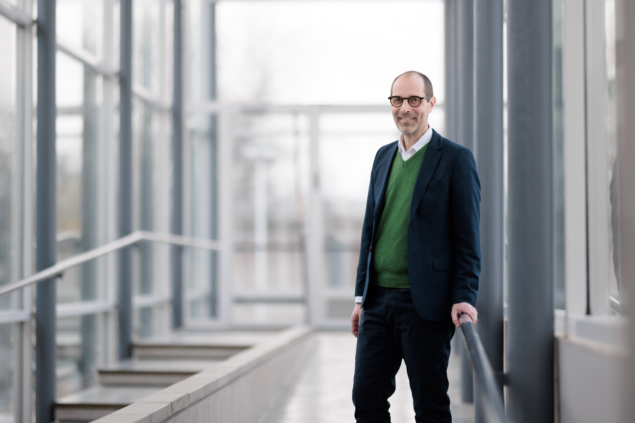 Dekaani Jaakko Järvi henkilökuvassa valoisalla lasiseinäisellä käytävällä kampuksella