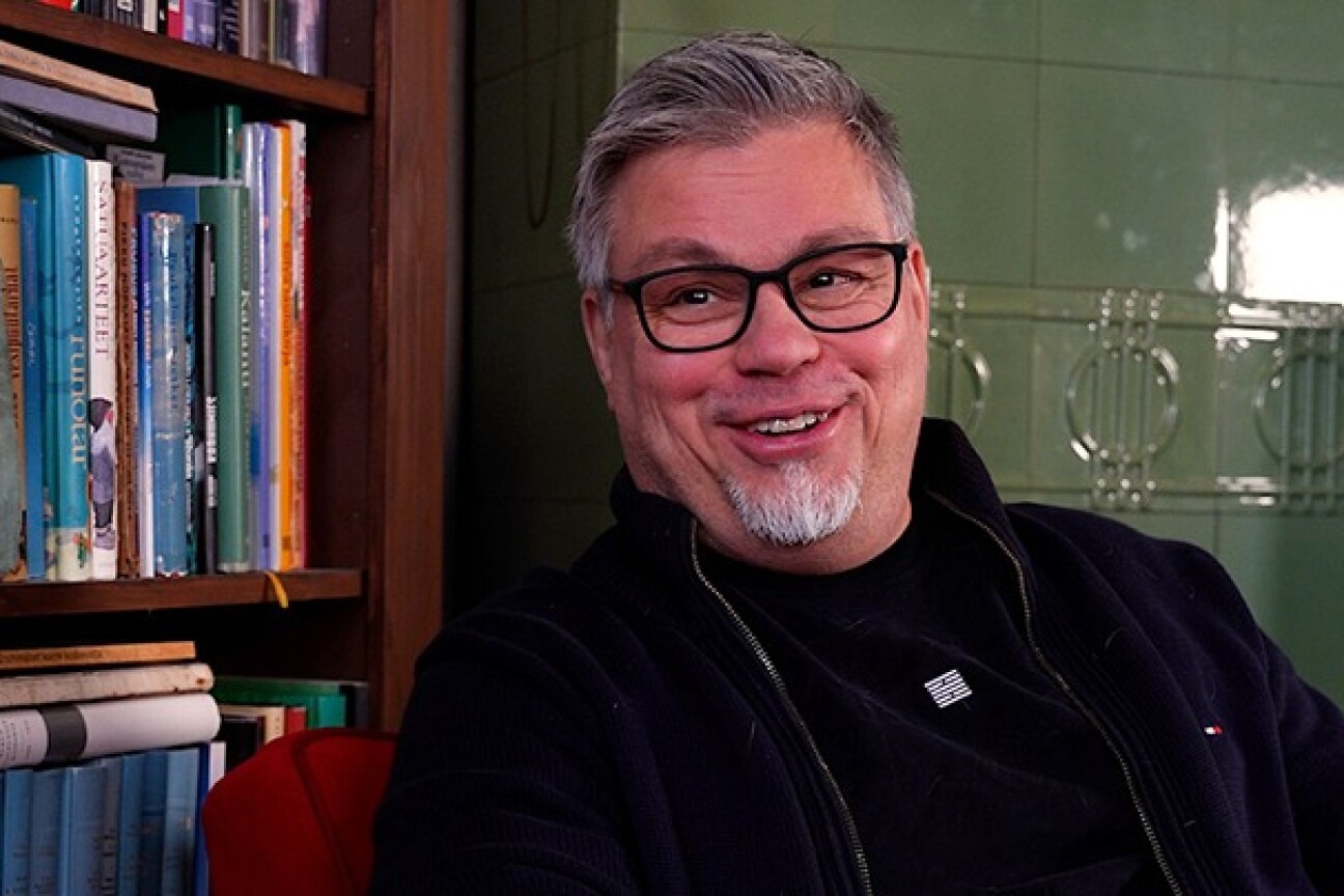 Tommi Kinnunen istuu kirjahyllyn edessä