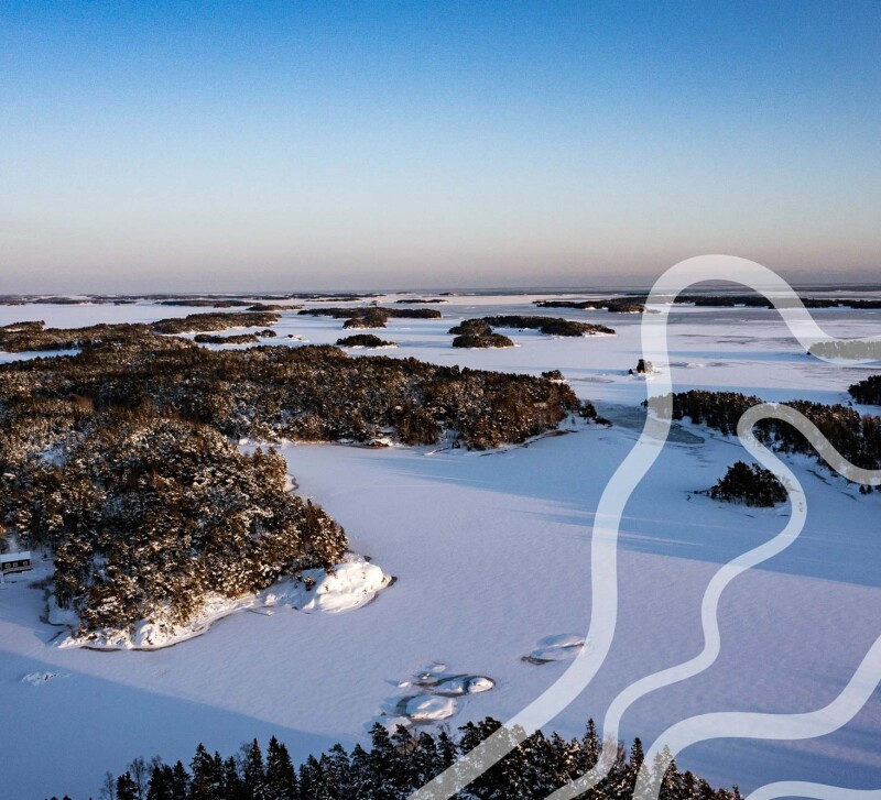 ilmakuvassa luminen saaristomaisema jossa meri jäässä ja lumen peitossa