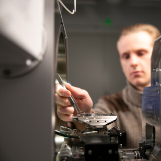 Tutkimusavustaja asettaa näytettä elektronimikroskooppiin
