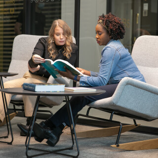 Kaksi opiskelijaa istuu nojatuoleissa ja  tutkii yhdessä kirjaa