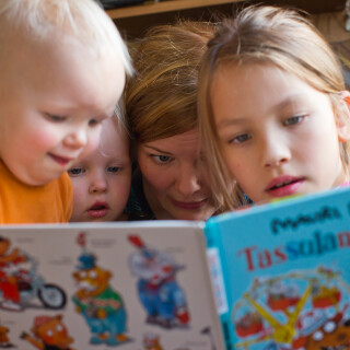 A mom reading a book with her children