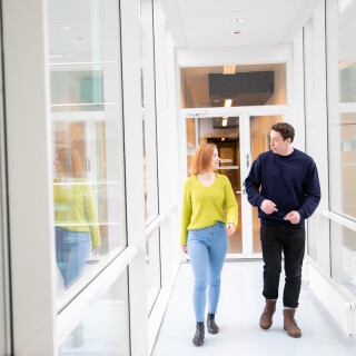 Mies ja nainen kävelevät valoisalla käytävällä