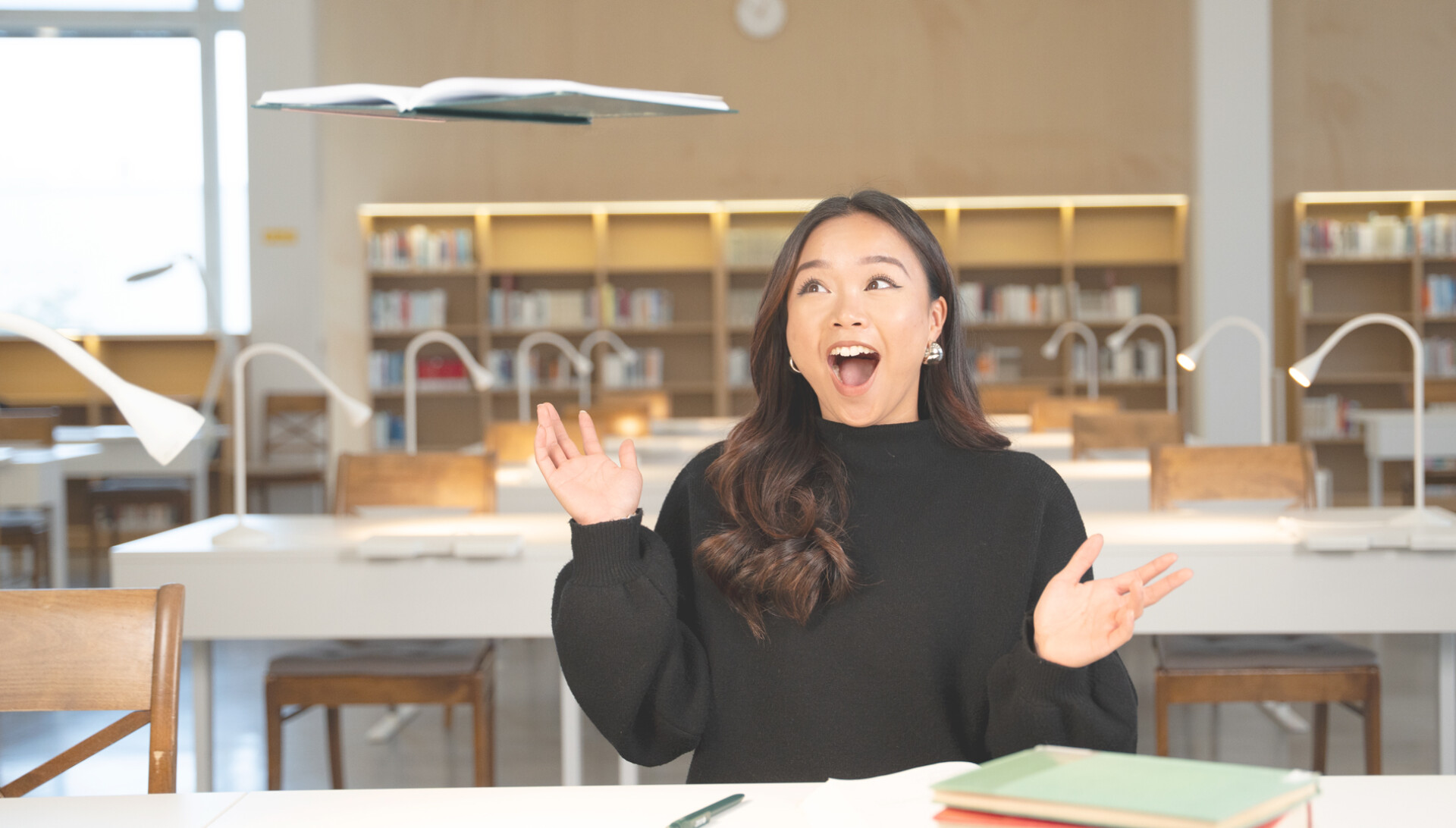 Henkilö katsoo hämmästyneenä leijuvaa muistikirjaa.